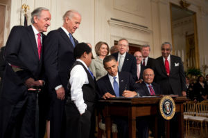 President Obama signing the ACA into law.