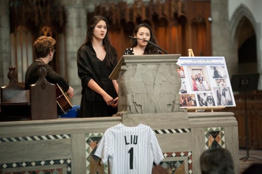 Genevieve Liu (center, at podium) sings at a memorial service for her father in Chicago. Photo credit: Jamie Manley/Chicago Maroon
