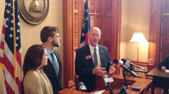 Rep. Allen Peake speaks with reporters while Dr. James Smith and his wife, Courtney, look on.