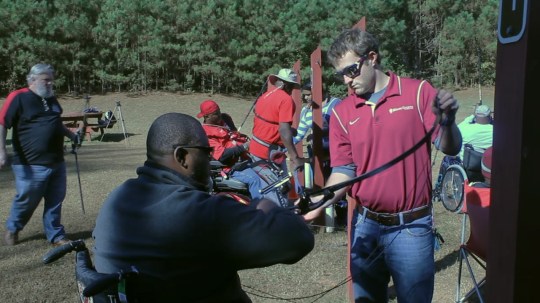 Sam Zapatka helps a veteran with his bow during archery practice at Panola Mountain State Park