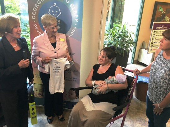 Dr. Brenda Fitzgerald (left) and Mrs. Sandra Deal (holding gown) at Safe Sleep event.